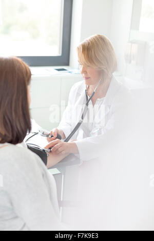 Arzt überprüft Patient Blutdruck im Untersuchungsraum Stockfoto