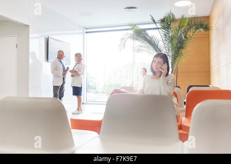 Frau am Handy im Krankenhaus lobby Stockfoto