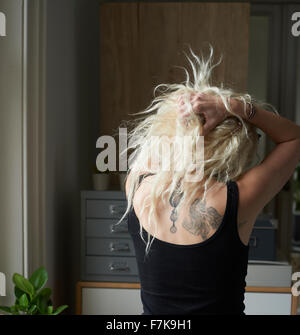 Junge Frau mit Händen im Haar rücken Tätowierungen enthüllt