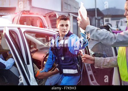 Rettungskräfte mit IV Tasche tendenziell Auto Unfallopfer Stockfoto