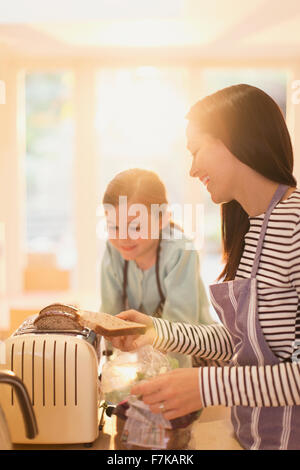 Mutter und Tochter Toasten von Brot in Küche Stockfoto
