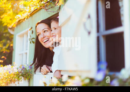 Lächelnde Mutter und Tochter im Spielhaus-Fenster Stockfoto