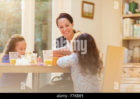 Arbeitende Mutter und Töchter am Frühstückstisch Stockfoto