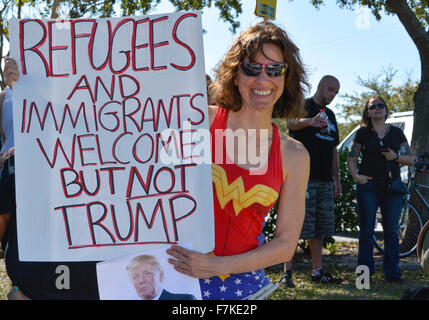 Frau im farbenfrohen Wonder Woman-Kostüm hält ein Protestschild mit der Aufschrift „Flüchtlinge und Einwanderer willkommen, aber NICHT TRUMP“ bei der GOP Florida Rally Stockfoto