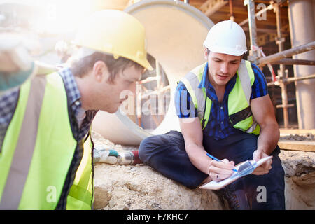 Bauarbeiter mit Zwischenablage sprechen auf Baustelle Stockfoto