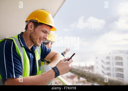 Bau Arbeiter SMS auf Hochhaus-Baustelle Stockfoto