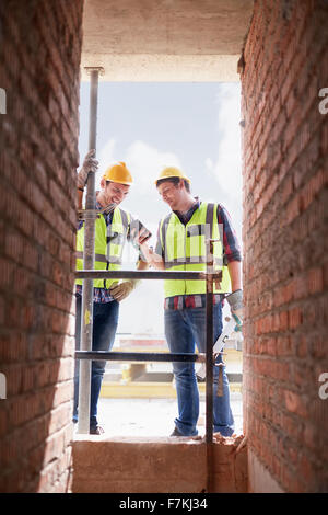 Bau-Arbeiter-SMS mit Handy auf Baustelle Stockfoto