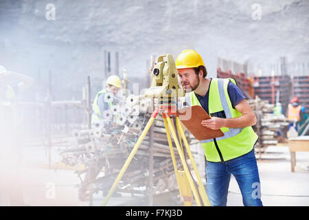 Ingenieur mit Zwischenablage mit Theodolit auf Baustelle Stockfoto