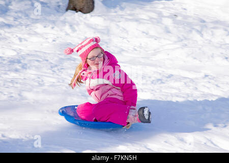 Kleines Mädchen in rosa Schneeanzug gleitet bergab im frischen Schnee in der Nähe von Lexington, Ma., New England, USA Stockfoto