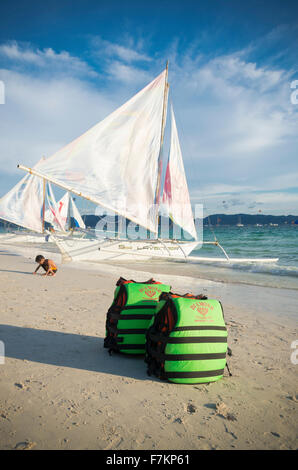 BORACAY, Philippinen - 20. Mai 2015: Grüne Schwimmwesten an einem tropischen Strand mit einigen Segelbooten im Hintergrund Stockfoto