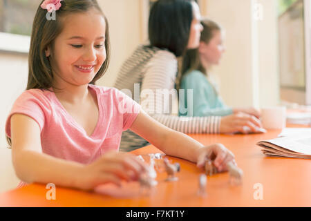 Lächelndes Mädchen spielen mit Miniatur-Spielzeug-Tiere Stockfoto