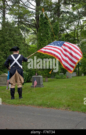 Eine revolutionäre Reenactor ehrt tot mit einer amerikanischen Flagge außerhalb Lexington, MA am Memorial Day 2011 Stockfoto