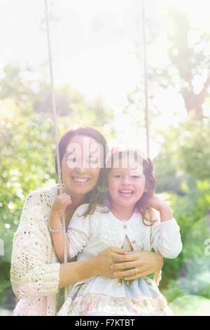 Porträt lächelnde Mutter umarmt Tochter auf Schaukel im park Stockfoto