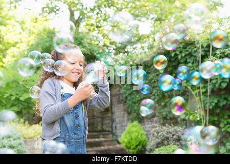 Mädchen bläst Luftblasen im Hinterhof Stockfoto