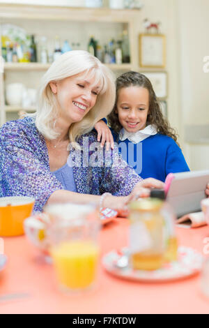 Großmutter und Enkelin mit digital-Tablette am Frühstückstisch Stockfoto