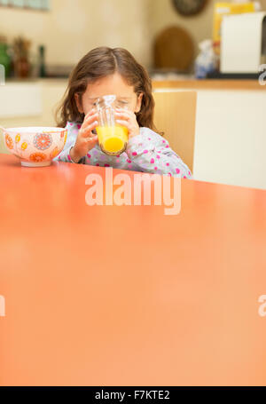 Mädchen trinken Orangensaft am Frühstückstisch Stockfoto