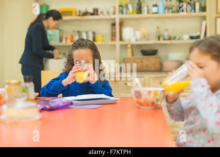 Mädchen trinken Orangensaft am Frühstückstisch Stockfoto