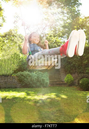 Begeisterte Mädchen schwingen im sonnigen Hinterhof Stockfoto