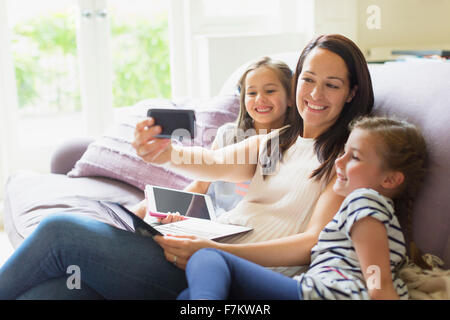 Mutter und Töchter unter Selfie auf Sofa im Wohnzimmer Stockfoto