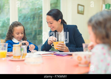 Arbeitende Mutter und Tochter Hausaufgaben am Frühstückstisch Stockfoto