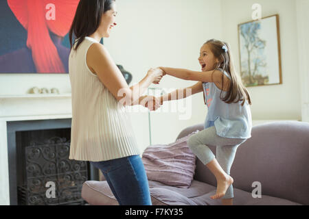 Spielerische Mutter und Tochter im Wohnzimmer tanzen Stockfoto