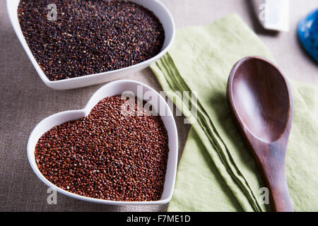 Herzförmige Schalen mit gesunde rote und schwarze Quinoa-Samen. Stockfoto