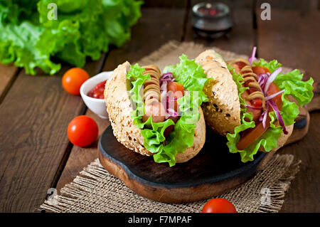 Würstchen mit Ketchup, Senf und Salat auf hölzernen Hintergrund Stockfoto