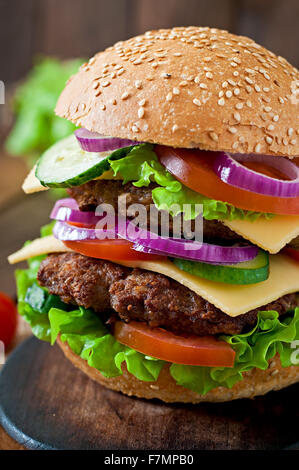 Große saftige Hamburger mit Gemüse und Rindfleisch auf einem hölzernen Hintergrund im rustikalen Stil Stockfoto