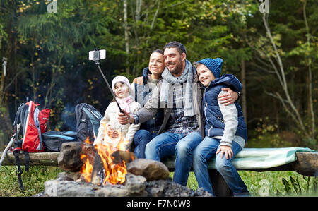 Familie mit Smartphone unter Selfie nahe am Lagerfeuer Stockfoto
