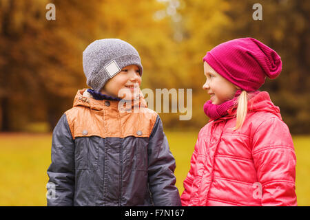 glückliche kleine Mädchen und Jungen reden im Herbst park Stockfoto