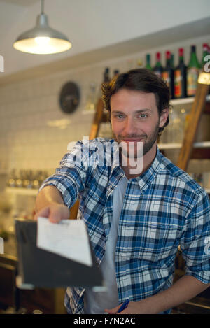 Ladenbesitzer präsentiert Rechnung an Kunden Stockfoto