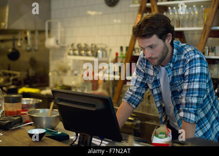 Café-Besitzer, die Kasse zu betrachten Stockfoto