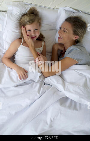 Mutter und Tochter zusammen im Bett liegend Stockfoto