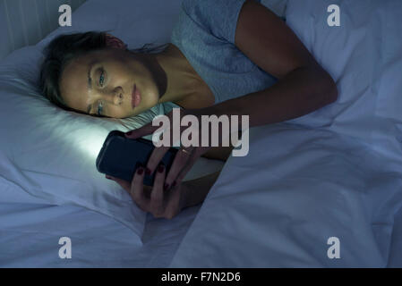 Frau im Bett mit smartphone Stockfoto