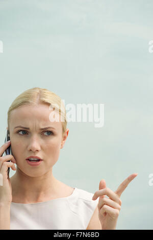 Frau macht wütendes Gesicht während des Gesprächs auf Handy Stockfoto