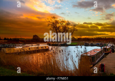 Morgengrauen in Rufford, Burscough, Lancashire, Großbritannien, Dezember 2015. Eine Pause im Wetter mit einem relativ ruhigen Start und einem gedämpften Sonnenaufgang, der warme Reflexionen auf dem Yachthafen erzeugt. Fettlers Wharf & Scarisbrick Marina befinden sich im Nordwesten Englands am Leeds Liverpool Canal, In der Nähe von Ormskirk. Der Yachthafen befindet sich im historischen Dorf Rufford in der Nähe der alten Halle von Rufford und ist ein familiengeführtes Unternehmen mit Anlegeplätzen für 100 Fahrzeuge bis zu 60 Fuß Länge, das sowohl schmale als auch breite Boote und Kanalkreuzer unterbringen kann. Stockfoto