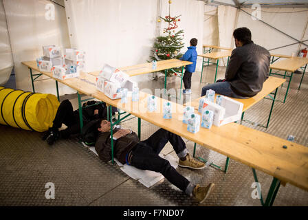 Berlin, Deutschland. 2. Dezember 2015. Ein junger Flüchtling junge zeichnet sich durch einen Weihnachtsbaum in den Vordergrund Flüchtlinge Schlaf auf dem Boden unter einem Tisch durch eine Heizung Vent in einem Zelt vor dem Landesamt für Gesundheit und Soziales (LaGeSO) in Berlin, Deutschland, 2. Dezember 2015. Flüchtlinge können registrieren oder Ausgangsunterstützung Empfangsdienste im Büro am Berliner Turm-Straße. Foto: KAY NIETFELD/Dpa/Alamy Live News Stockfoto