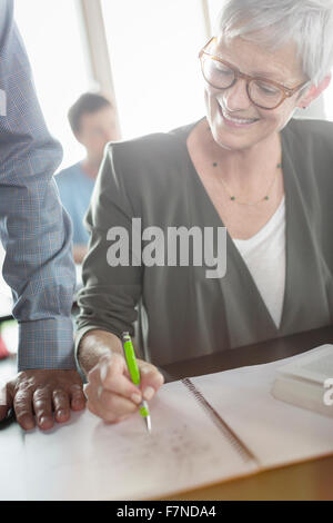 Ältere Frau, die Überprüfung der Hausaufgaben in Erwachsenenbildung Klassenzimmer Stockfoto