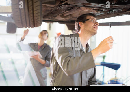 Mechaniker arbeiten unter Auto in Auto-Werkstatt Stockfoto