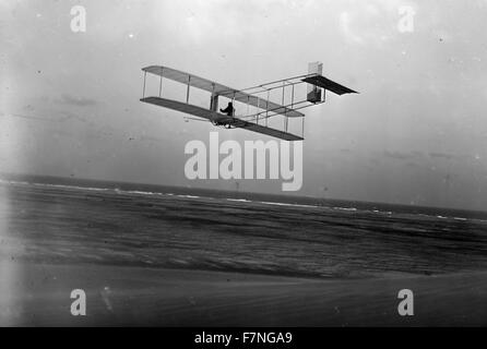 Linken hinteren Dreiviertelansicht der Gleitschirm im Flug in Kitty Hawk, North Carolina. Orville, begleitet von seinem Bruder Lorin, seinem Neffen Horace und seinem Freund Alexander Ogilvie, von England, kam zur Durchführung von gleiten Experimente mit einem Segelflugzeug Wright 1911 angetriebene Maschine ähnlich aber es mangelt an seinem Motor... Stockfoto