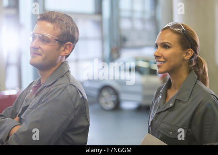 Lächelnd Mechanik wegsehen in Autowerkstatt Stockfoto