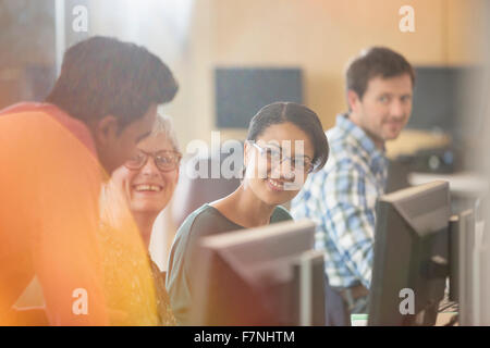 Lächelnde Studenten sprechen am Computer in Erwachsenenbildung Klassenzimmer Stockfoto