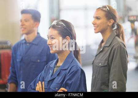 Lächelnd Mechanik wegsehen in Autowerkstatt Stockfoto