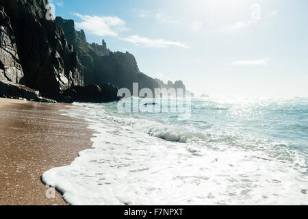 Welle im Pedn Vounder Beach, Süd Cornwall an einem hellen Oktobertag brechen. Niedrige Herbst Sonne schimmernd auf dem Meer. Stockfoto