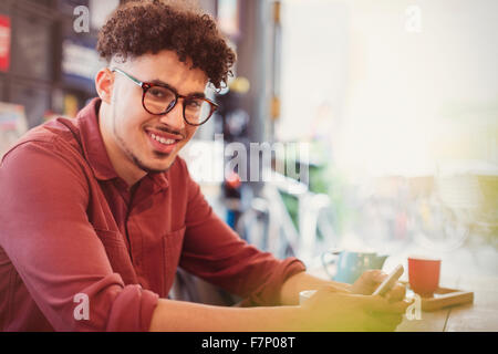 Porträt, Lächeln Mann mit lockiges schwarzes Haar SMS im café Stockfoto