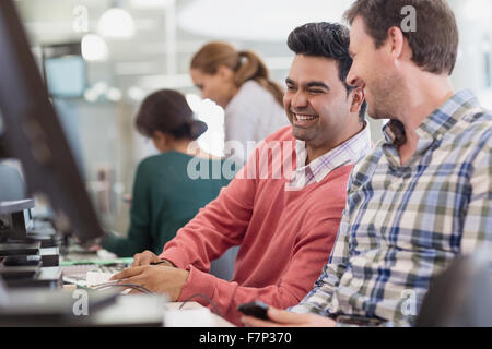 Männer lachen über Computer im Klassenzimmer der Erwachsenenbildung Stockfoto