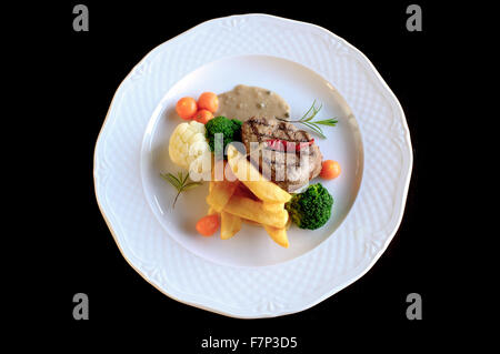 Rindersteak mit Bratkartoffeln und Gemüse im weißen Teller Stockfoto