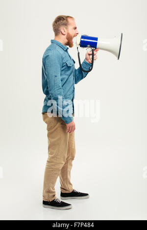 Seite Ansicht Porträt ein legerer Mann schreien im Megaphon isoliert auf weißem Hintergrund Stockfoto
