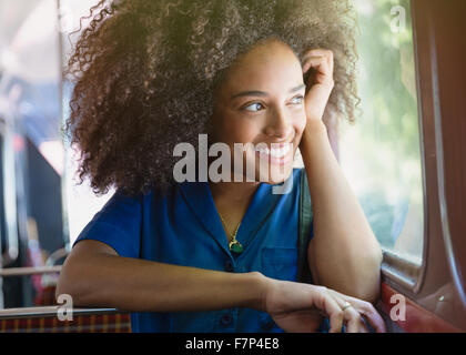 Lächelnde Frau mit Afro Reiten Bus suchen Fenster