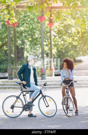 Freunde auf Fahrrädern sprechen im städtischen park Stockfoto